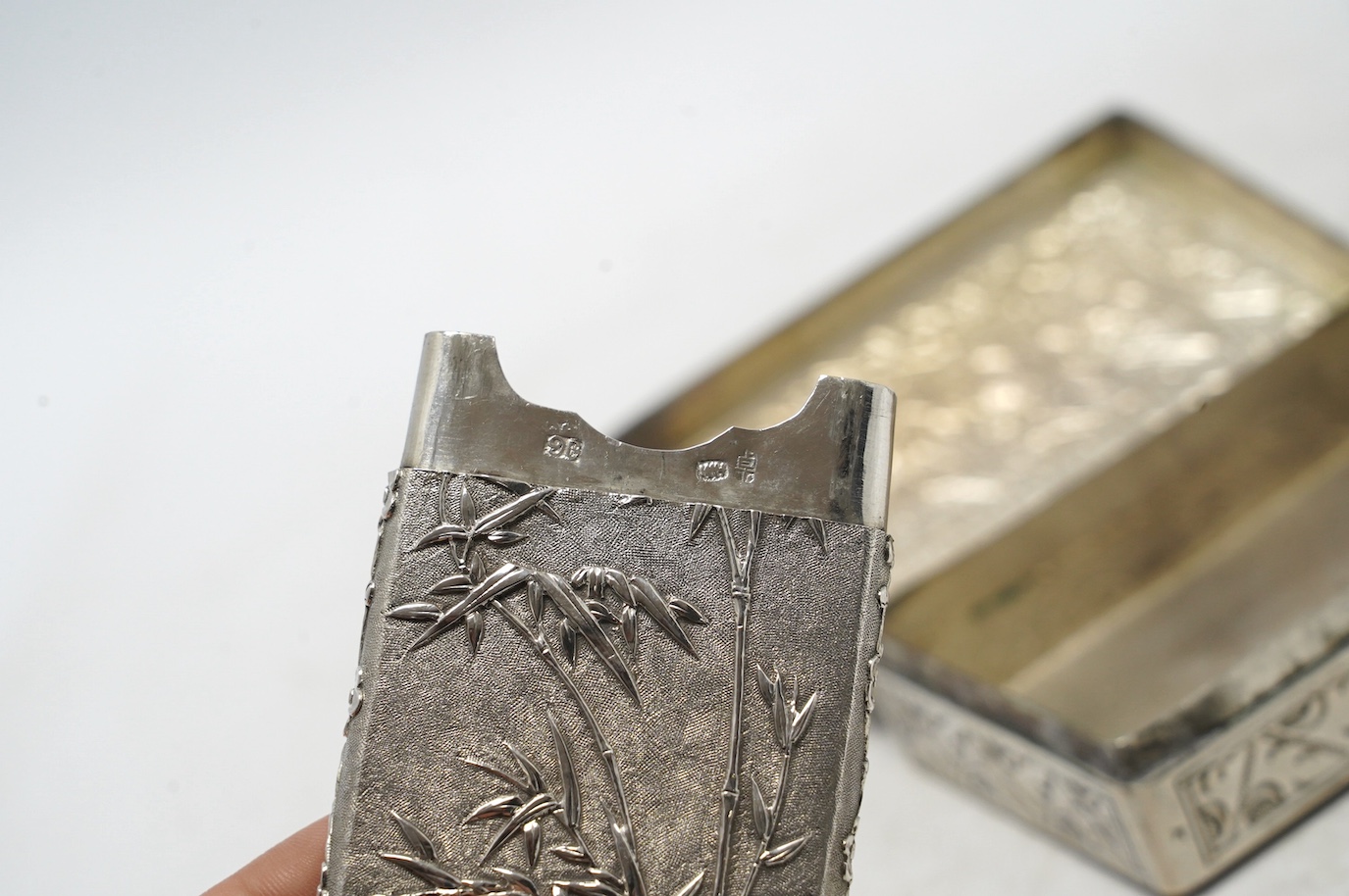 An early 20th century Chinese Export white metal card case by Wang Hing, 84mm, together with a Chinese white metal box with hinged cover. Condition - fair to good